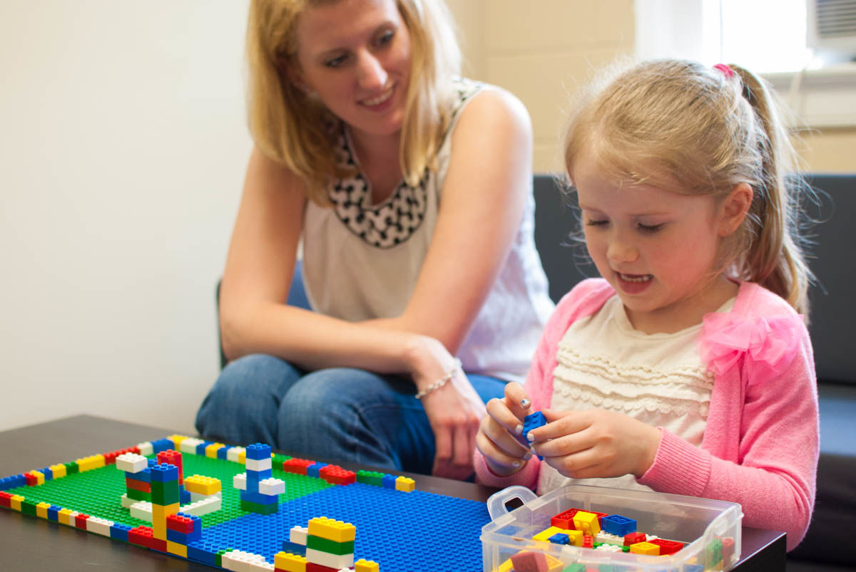 Jonna helps Macie explore with Legos.